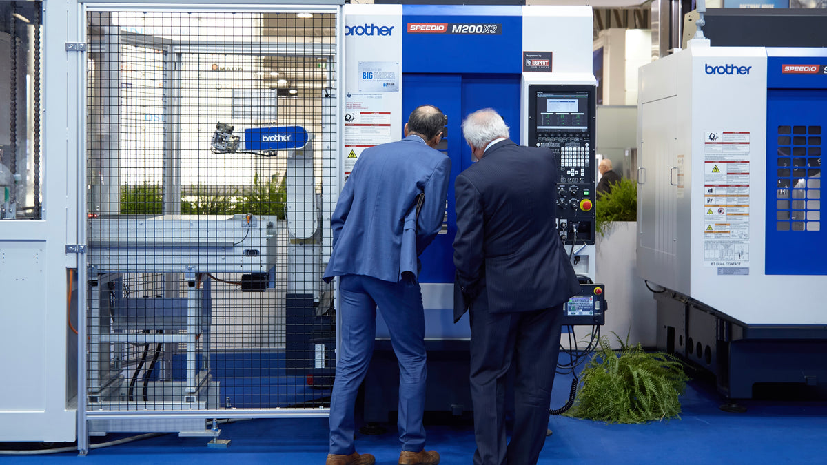 Visitatori osservano centro di lavoro allo stand in fiera – IMU International Macchine Utensili